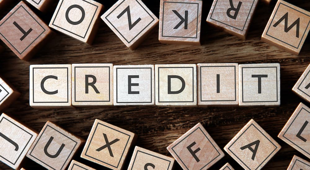 A close up shows wooden blocks that spell out credit.