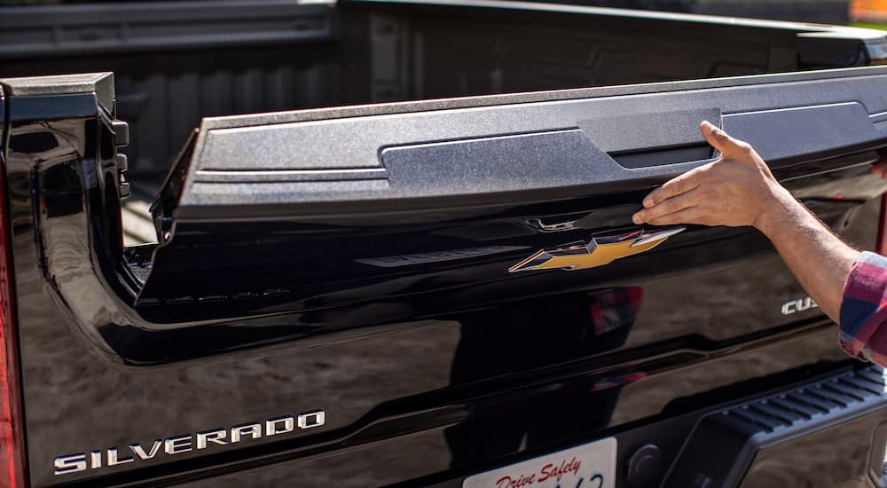 A close up of a 2022 Chevy Silverado 1500 HD shows a man lowering the tailgate.