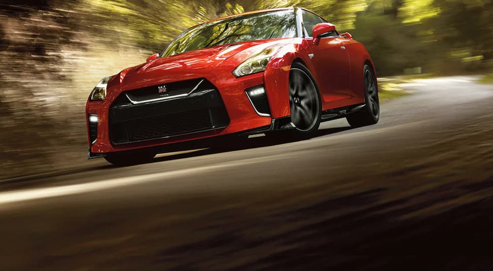 A red 2021 Nissan GT-R NISMO is shown driving to a Nissan dealer.
