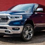 A blue 2021 Ram 1500 is shown parked in front of a red wall.