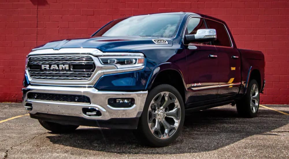 A blue 2021 Ram 1500 is shown parked in front of a red wall.