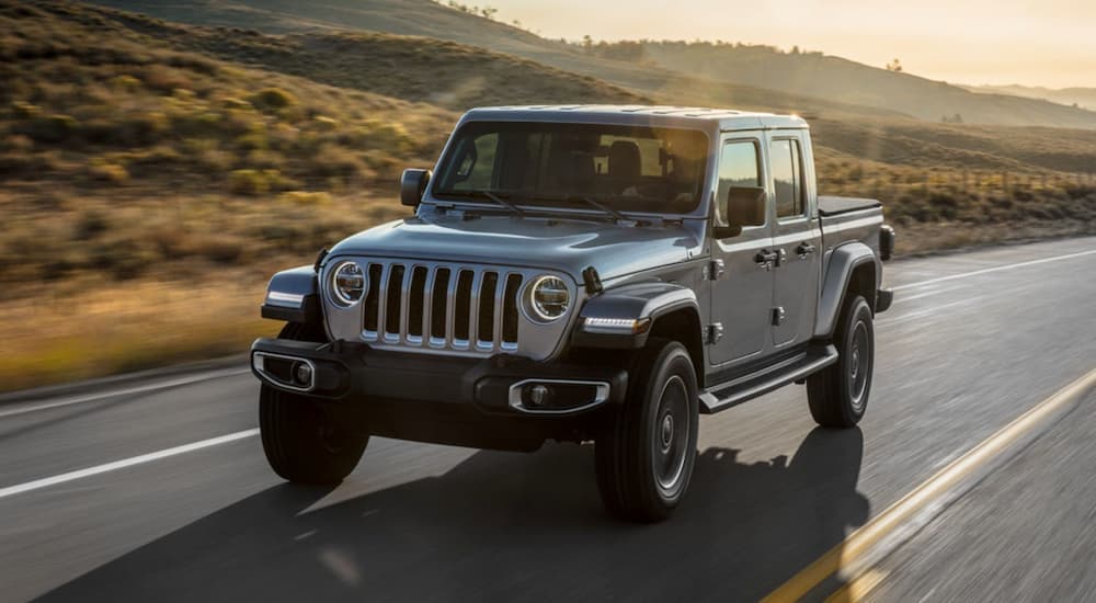 A silver 2020 Jeep Gladiator is driving down a two lane road.