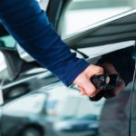 A person is opening a car door at a used car lot.