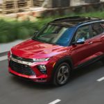 A red 2021 Chevy Trailblazer is shown from a high angle driving down a city road.