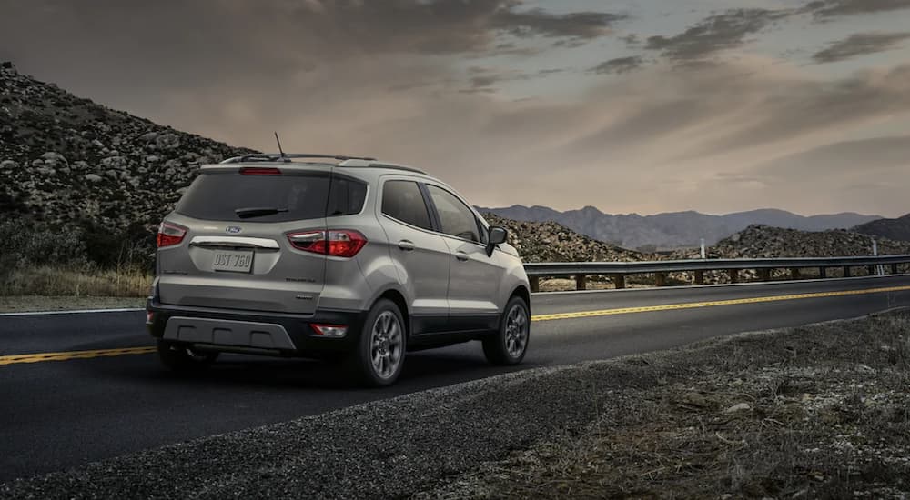 A silver 2021 Ford EcoSport is shown from behind driving on an open road.