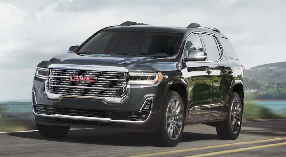 A black 2021 GMC Acadia is shown from the side driving on an open road.