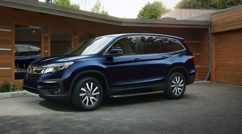 A blue 2021 Honda Pilot EX-L is shown from the side parked in front of a modern house.