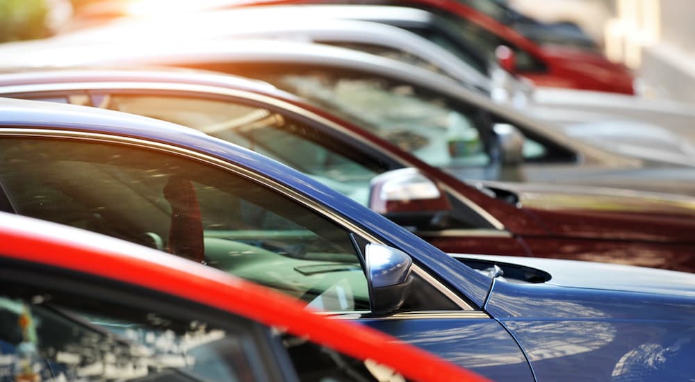 A row of new cars are shown parked at a car dealer.