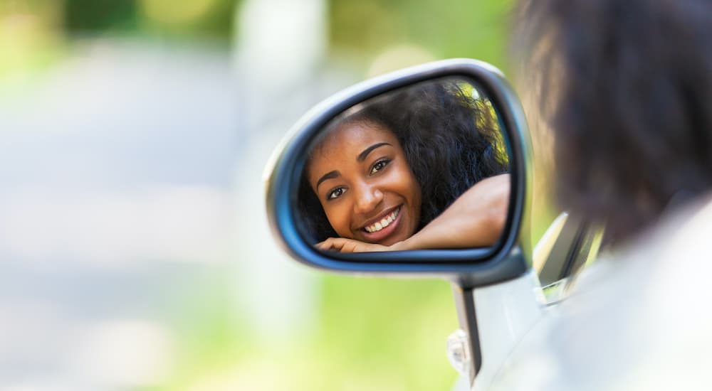 A teen driver is shown reflected in the drivers side mirror.