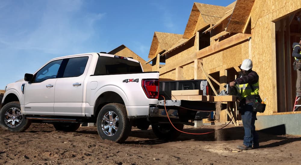 A white 2021 Ford F-150 is shown parked in front of an unfinished building.