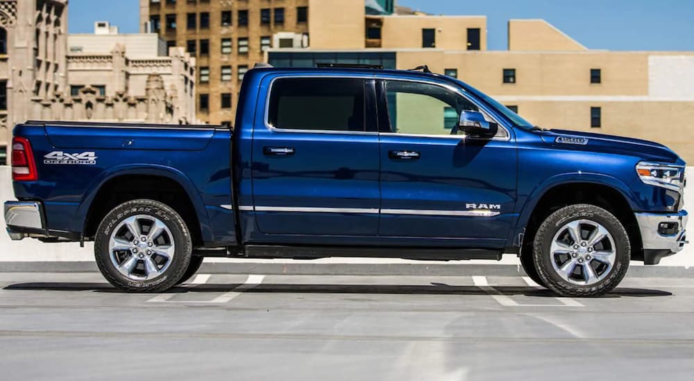 A blue 2021 Ram 1500 is shown from the side parked in a city after winning a 2021 Ram 1500 vs 2021 GMC Sierra 1500 comparison.