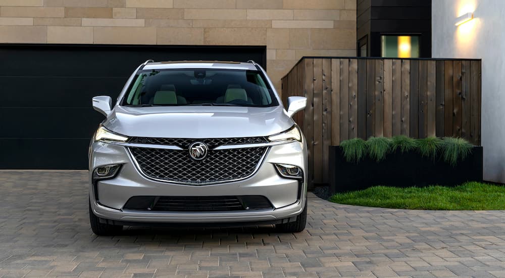 A silver 2022 Buick Enclave is shown from the front parked in front of a garage.