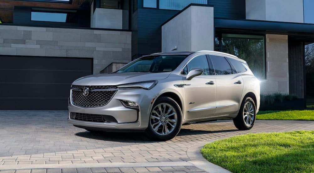 A silver 2022 Buick Enclave is shown from the side parked in front of a modern house.