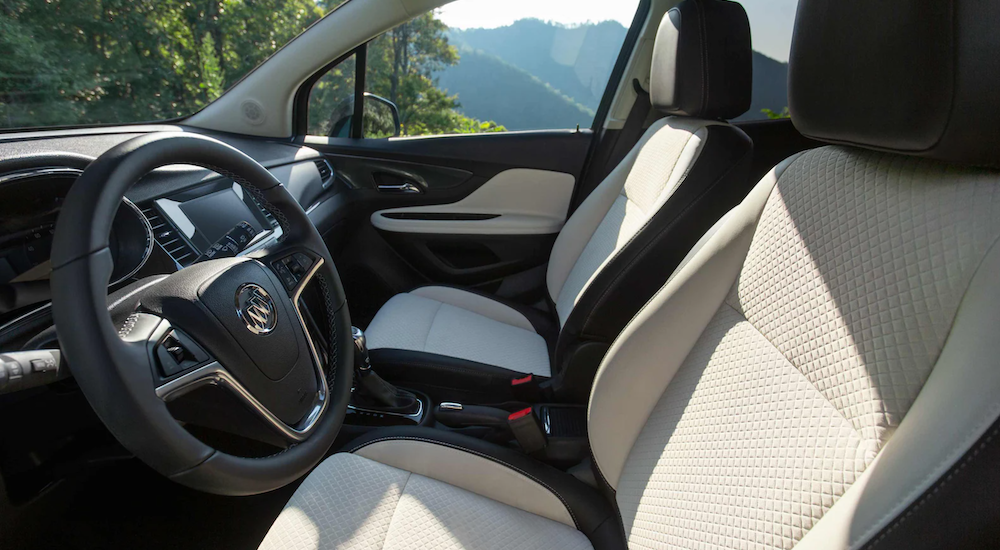 The white and black interior of a 2022 Buick Encore shows the steering wheel and infotainment screen. 