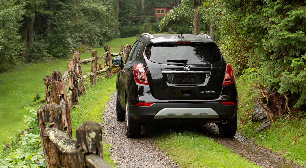 A black 2022 Buick Encore is shown from the rear driving on a dirt path.