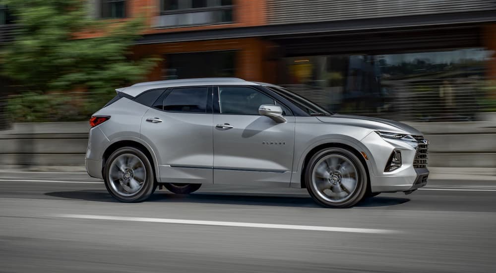 A silver 2022 Chevy Blazer is shown from the side driving through a city.