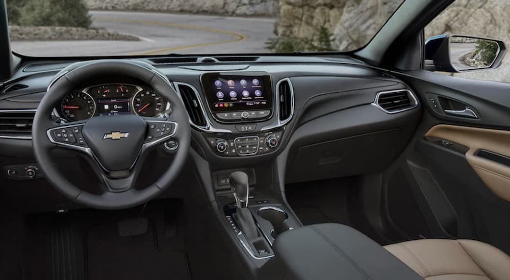 The black interior of a 2022 Chevy Equinox shows the steering wheel and infotainment screen.