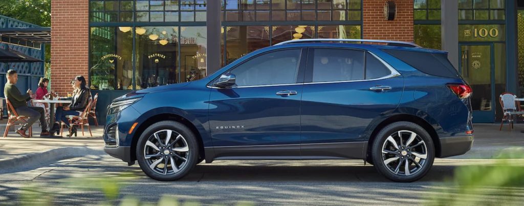 A blue 2022 Chevy Equinox is shown from the side parked in front of a modern building.