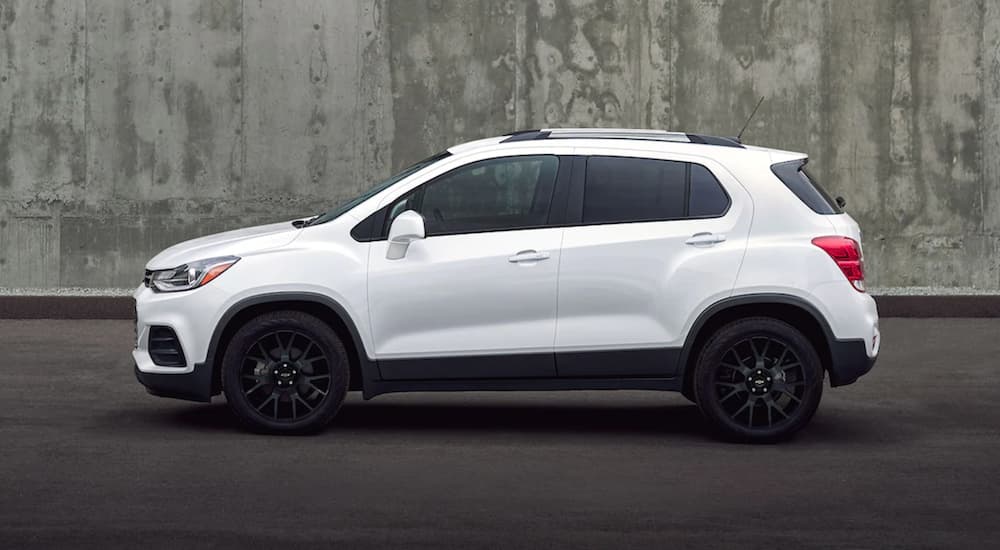 A white 2022 Chevy Trax is shown from the side parked in front of a cement wall.
