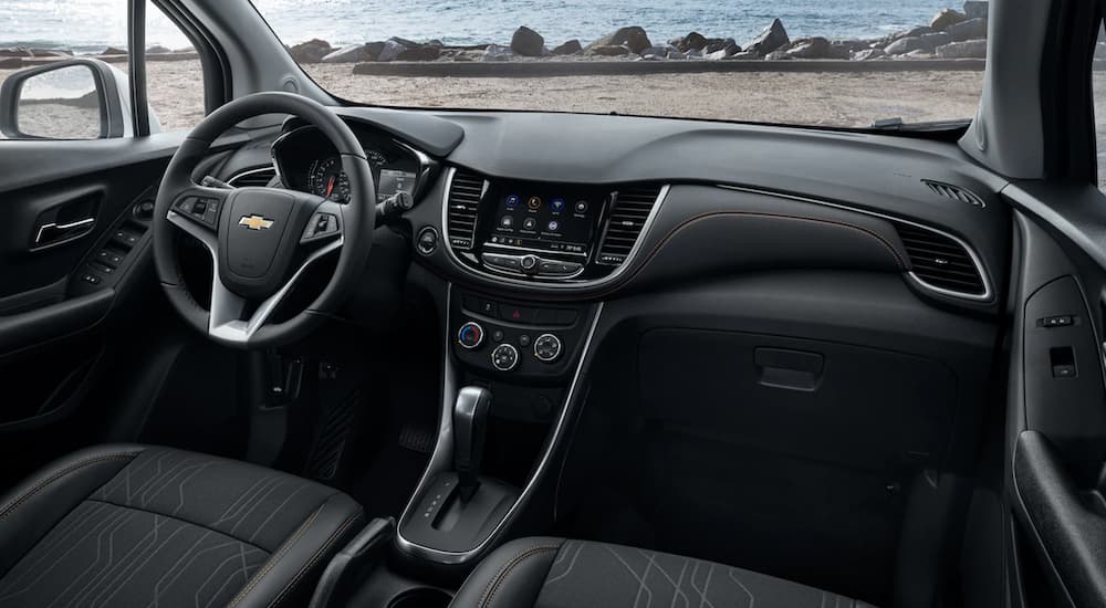 The black interior of a 2022 Chevy Trax shows the steering wheel and infotainment screen.