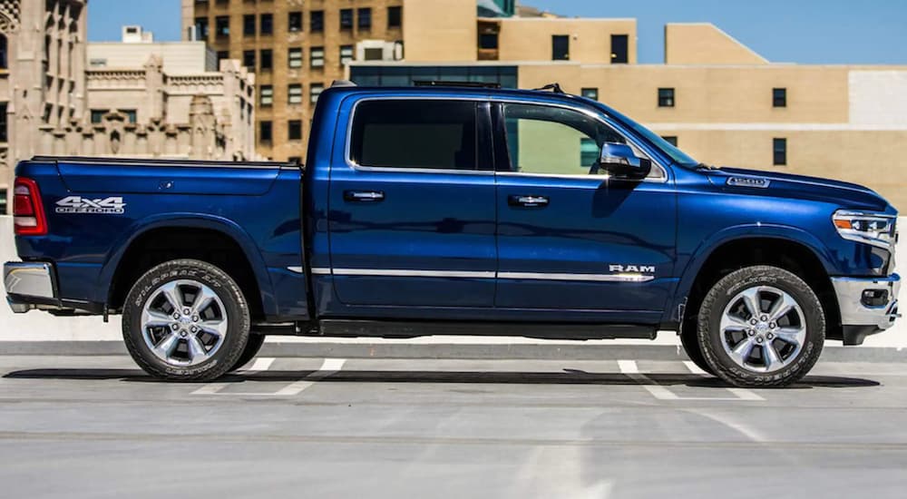A blue 2022 Ram 1500 is shown from the side parked in a city.