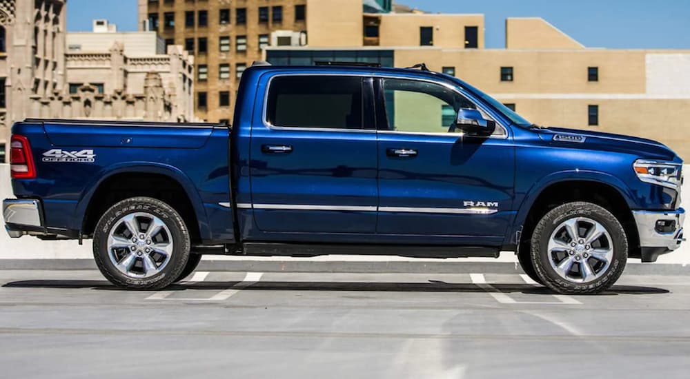A blue 2022 Ram 1500 is shown from the side parked in a city.