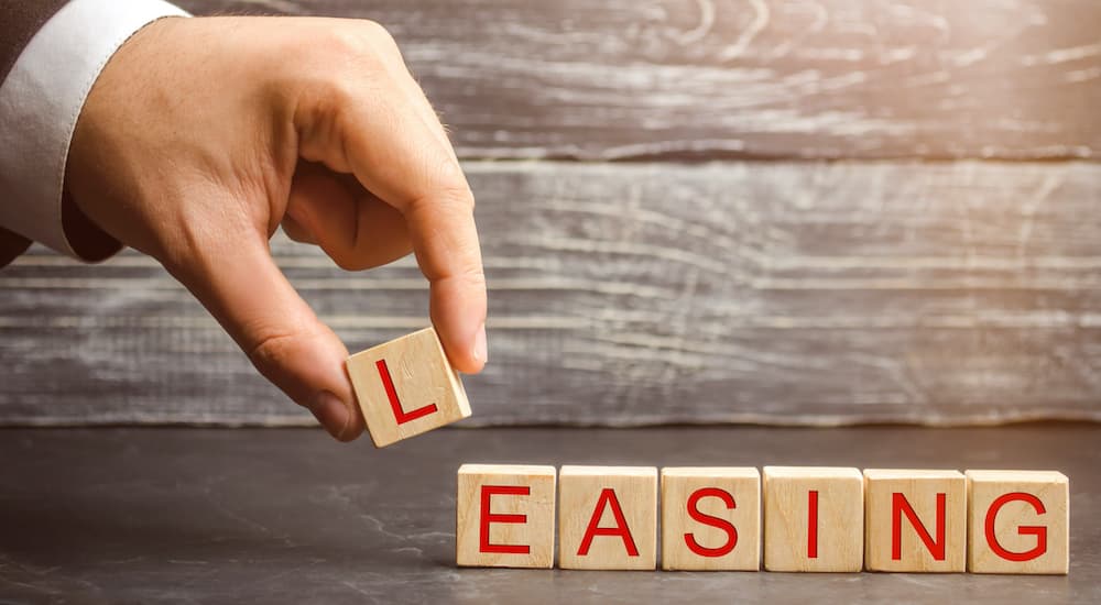 A hand is placing the block letter L to spell out leasing.