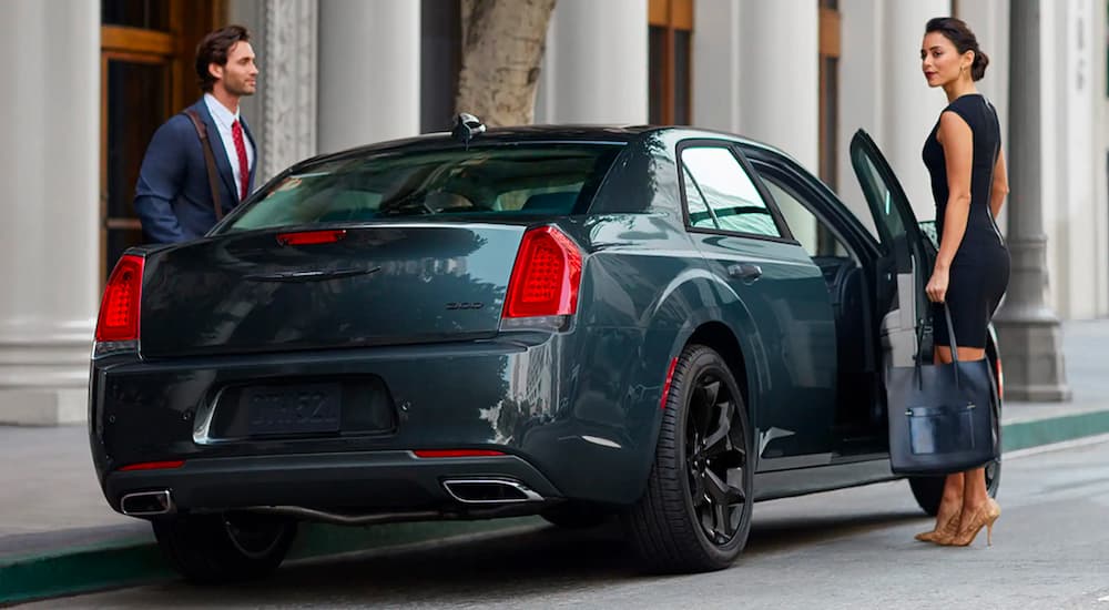 A couple is shown opening the doors on a grey 2021 Chrysler 300.