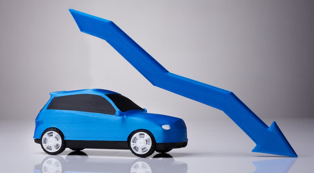 A blue toy SUV is shown next to a falling blue arrow.