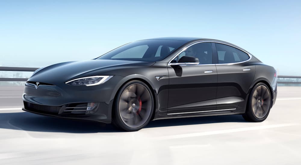 one of the most popular electric vehicles, a black 2021 Tesla Model S, is shown driving down a highway.
