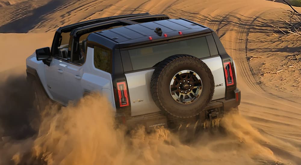 A white 2022 GMC Hummer EV is shown from the rear off-roading after leaving a GMC dealer.