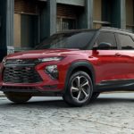 One of the most popular new cars in stock near you, a red 2021 Chevy Trailblazer RS, is shown parked on a brick pathway.