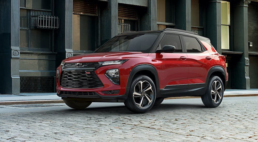 One of the most popular new cars in stock near you, a red 2021 Chevy Trailblazer RS, is shown parked on a brick pathway.