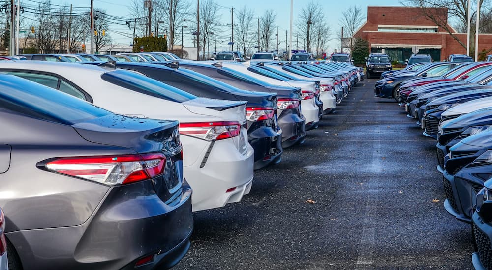 Two rows of cars are shown at a used car dealership.