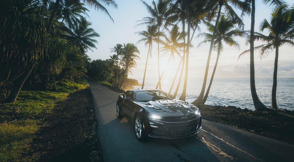 A grey 2020 Chevy Camaro SS is shown on a road near the ocean at sunrise.