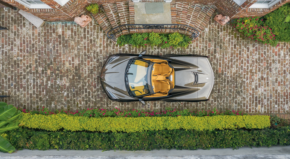 A tan 2020 Chevy Corvette is shown in an aerial view on a brick path after leaving a used car lot.