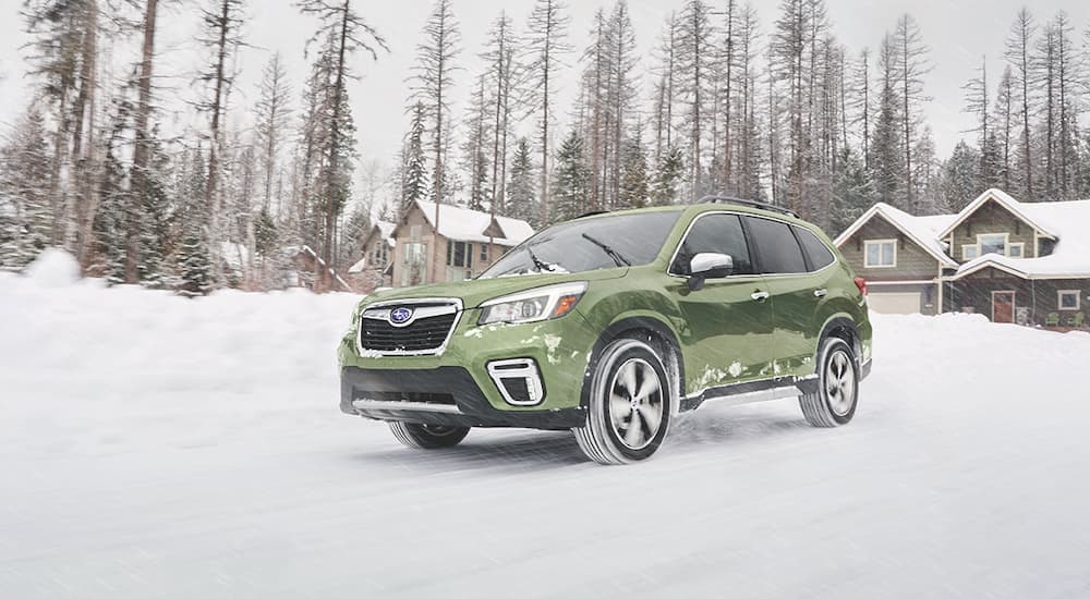 A green 2019 Subaru Forester is shown driving in the snow.