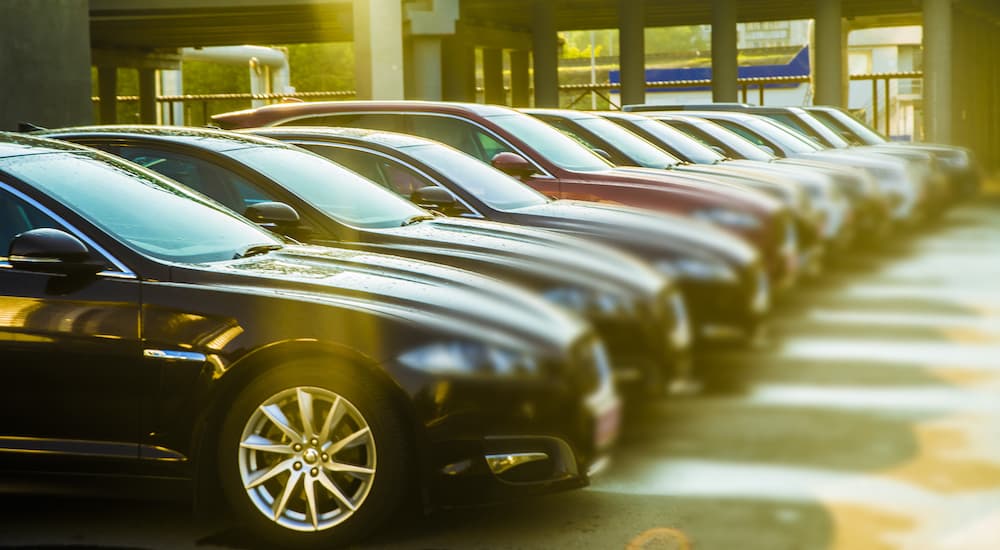 A row of cars are shown parked at a used car dealership.