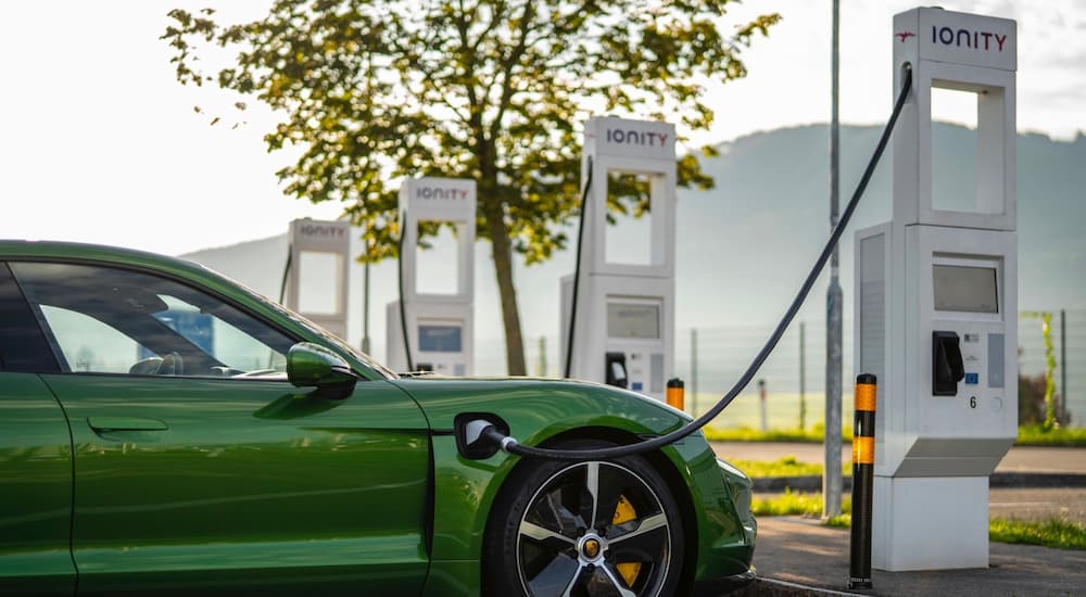 A green 2020 Porsche Taycan is shown parked at an electric charging station.