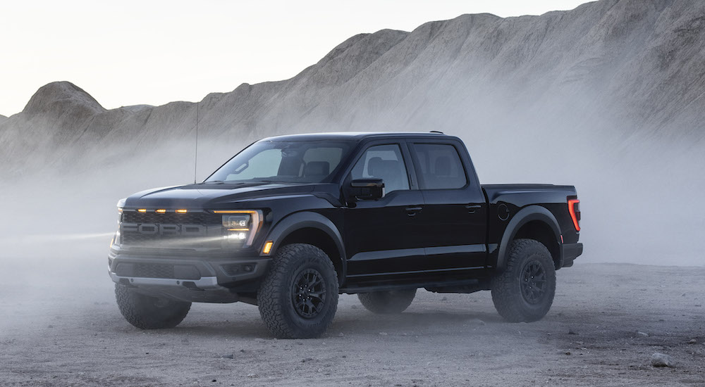 A black 2021 Ford F-150 Raptor is shown parked in a foggy trailside parking lot.