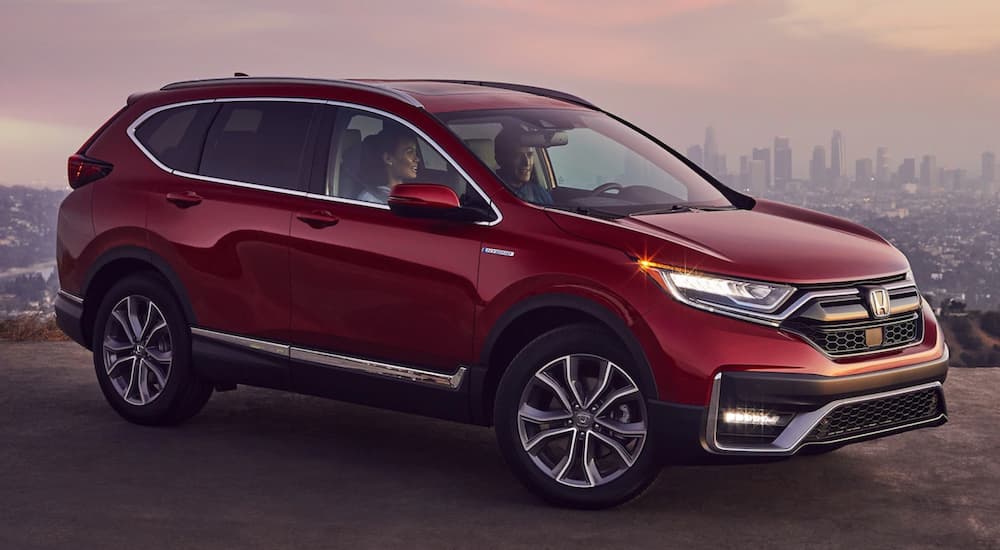 A red 2021 Honda CR-V Touring is shown from the side parked in front of a city.