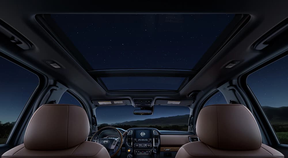 The tan interior of a 2021 Nissan Titan XD shows the moon roof at night.