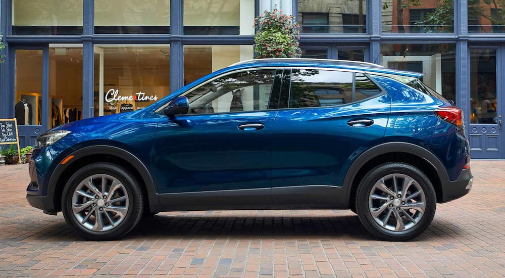 A blue 2022 Buick Encore GX is shown from the side parked in front of a modern building.