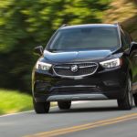 A black 2022 Buick Encore is shown driving on a country road.