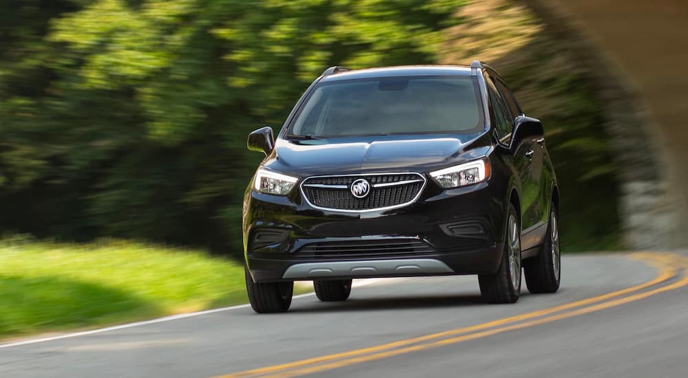 A black 2022 Buick Encore is shown driving on a country road.