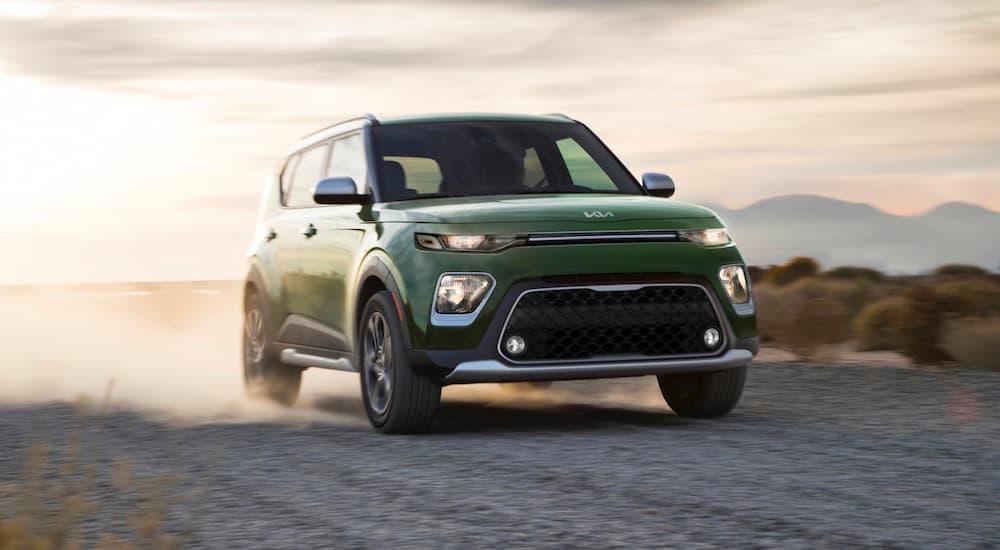 A green 2022 Kia Soul is shown driving on a desert road during a 2022 Buick Encore vs 2022 Kia Soul comparison.