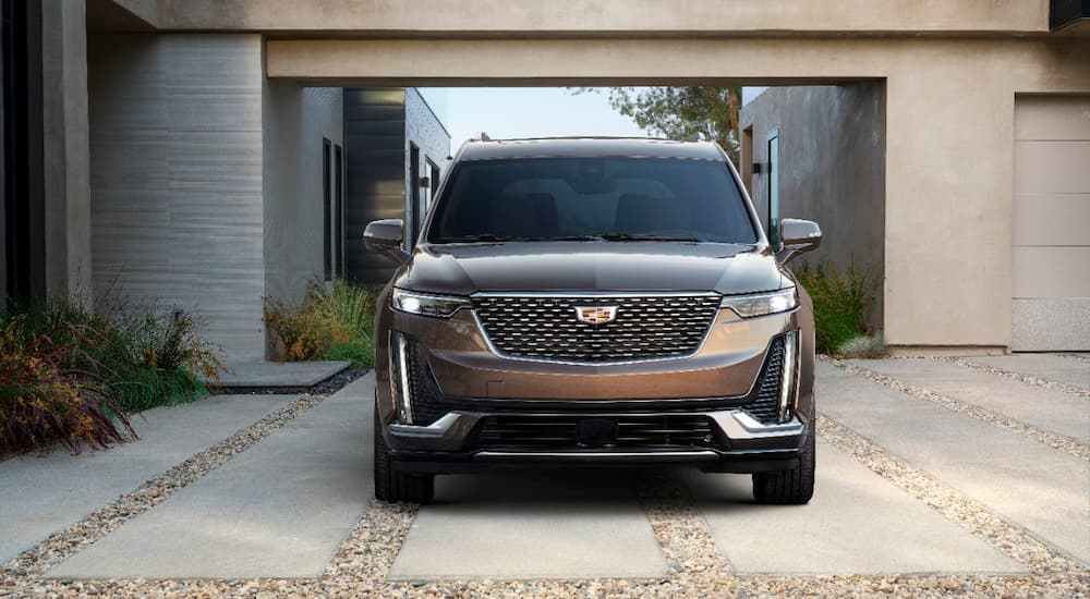 A brown 2022 Cadillac XT6 is shown from the front parked outside of a modern home.