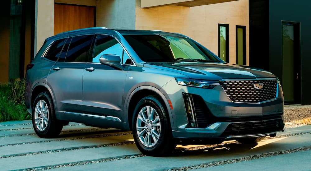 A silver 2022 Cadillac XT6 is shown from an angle parked outside of a modern home.