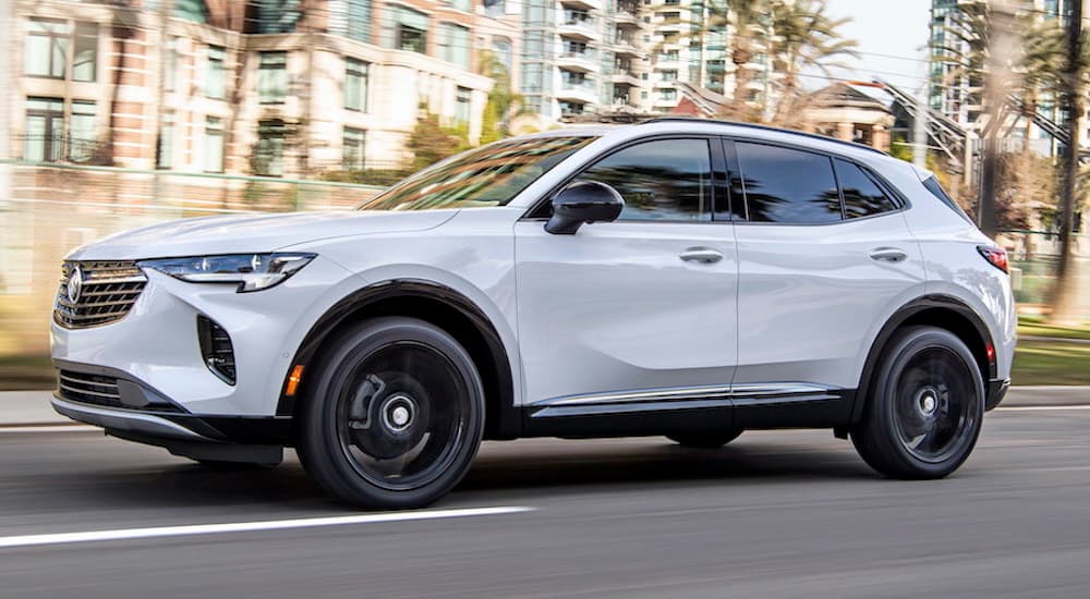 A white 2022 Buick Envision is shown from the side driving through a city.