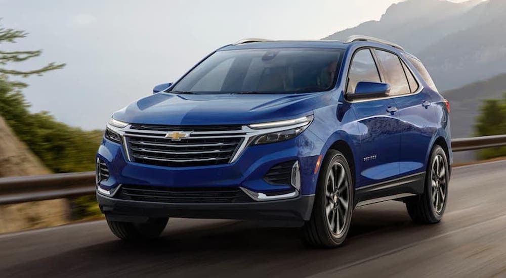 A blue 2022 Chevy Equinox is shown from the front driving on an open road after winning a 2022 Chevy Equinox vs 2022 Buick Envision comparison.